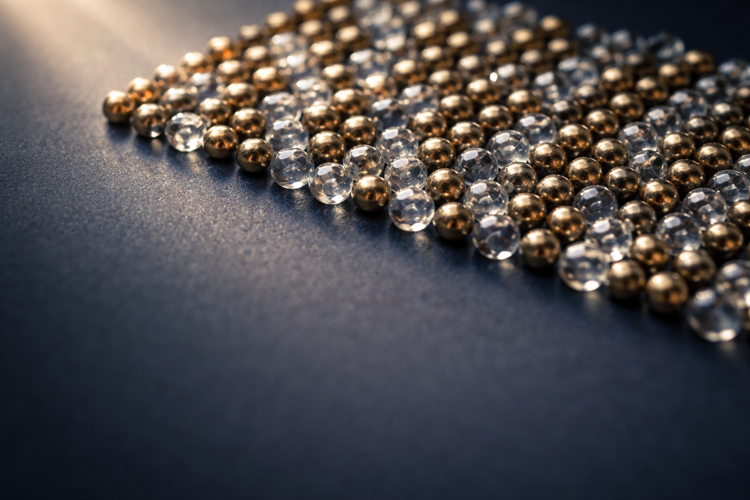High-angle macro photo of a dense cluster of glass and brass beads on a matte navy background, sharply focused in the upper two-thirds with soft blur and empty lower third for overlay.