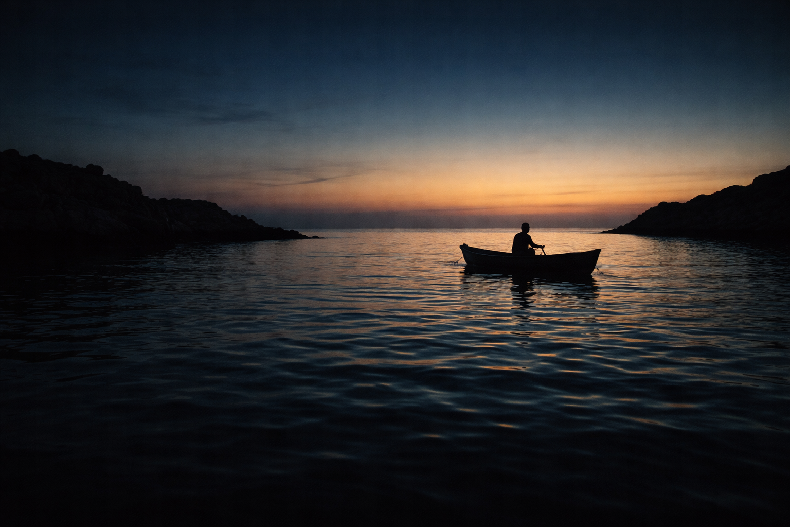 Dusk silhouette of a rocky coastline and a lone small fishing boat with an anonymous figure, rim-lit by warm light over calm blue water, with the lower third left empty and low-contrast.
