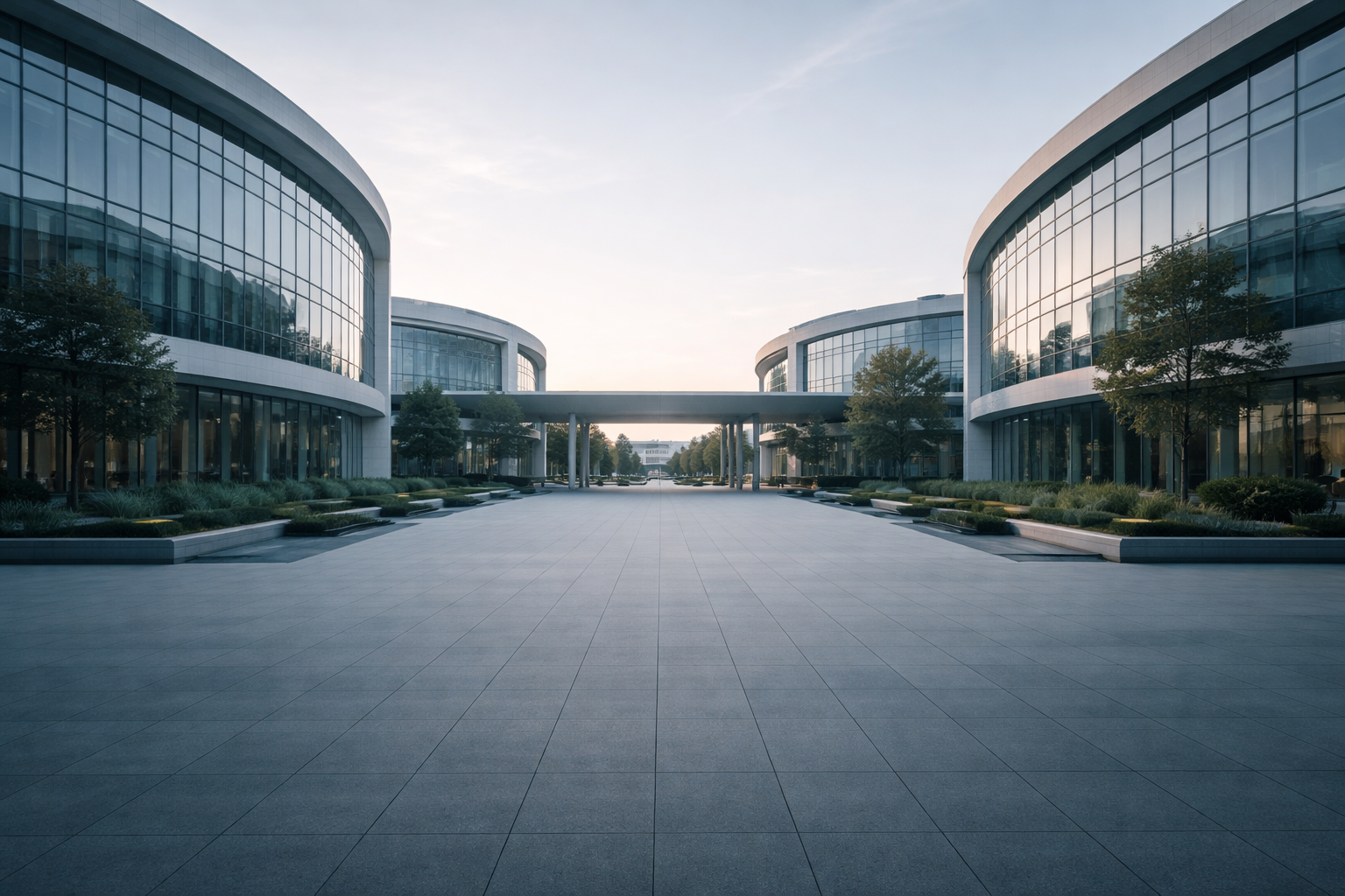 Wide view of a modern, anonymous research campus courtyard with curved glass-and-concrete facades under soft morning light, foreground kept empty and low-contrast while buildings and sky occupy the upper two-thirds.